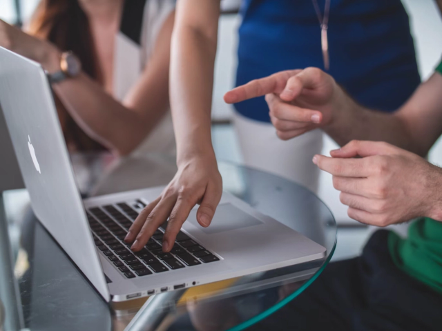 An image of three ladies using a gray laptop