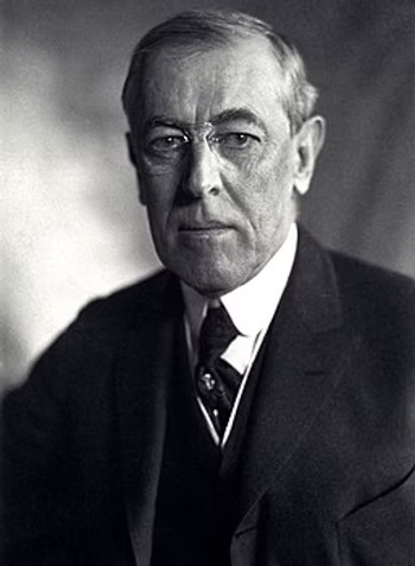 Formal black and white portrait of Woodrow Wilson in a dark suit and tie, circa early 1900s.
