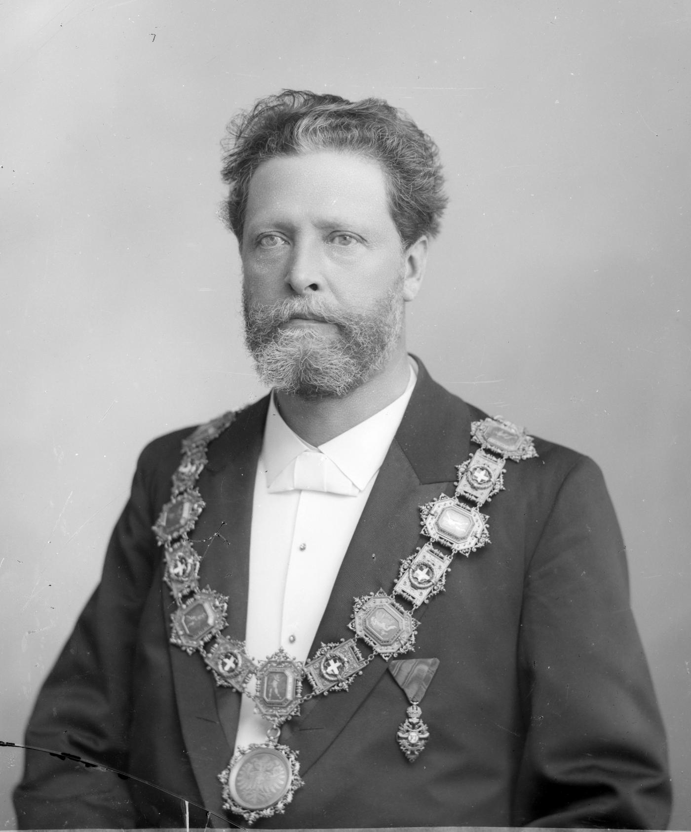 Black-and-white portrait of a bearded man in evening dress wearing a heavy ceremonial chain of office across his chest