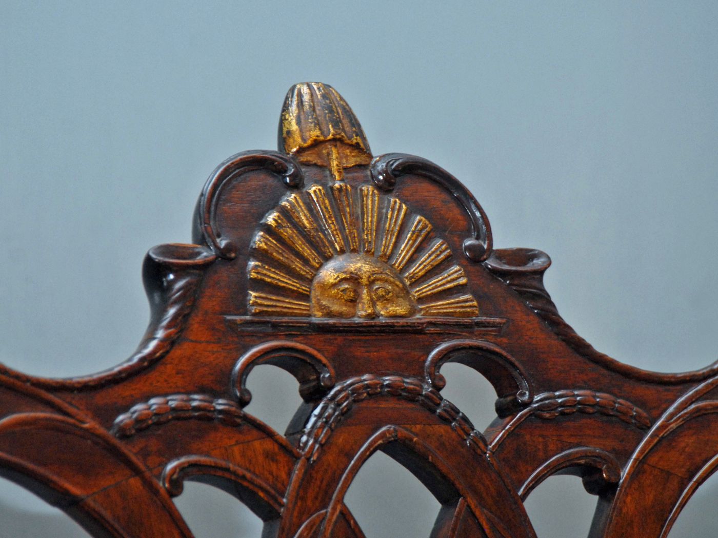 Gilded half-sun with rays carved into the top rail of a wooden chair, topped by a liberty pole and cap