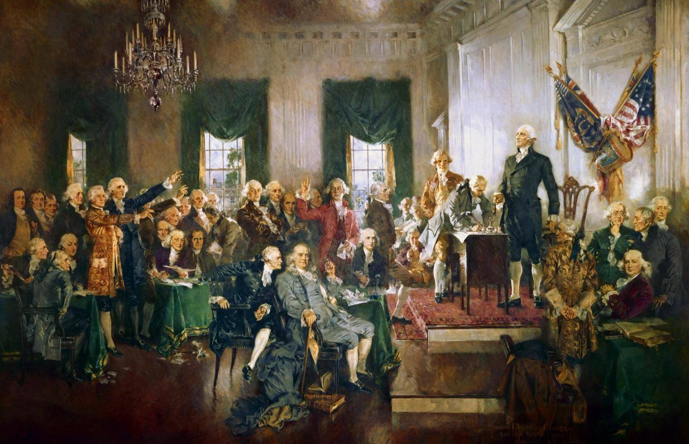 Large painting of delegates in eighteenth-century dress gathered in a sunlit assembly room, with George Washington standing on a raised platform beside a desk where the Constitution is being signed