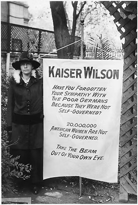Woman suffragist holding sign criticizing Kaiser Wilson and advocating for women's voting rights, circa 1910s-1920s.
