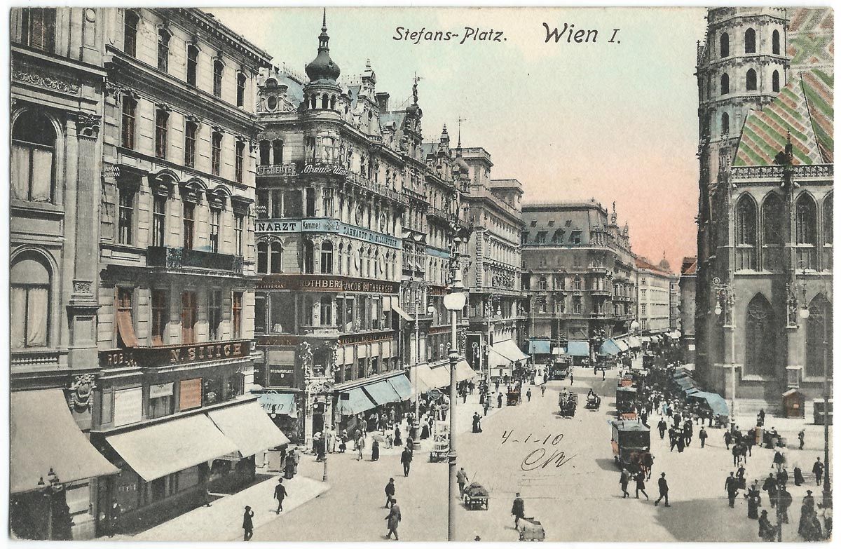 Hand-coloured postcard of a busy Vienna square lined with tall ornate buildings and shop awnings, with horse-drawn cabs and pedestrians, and the Gothic tower of St. Stephen's Cathedral at right