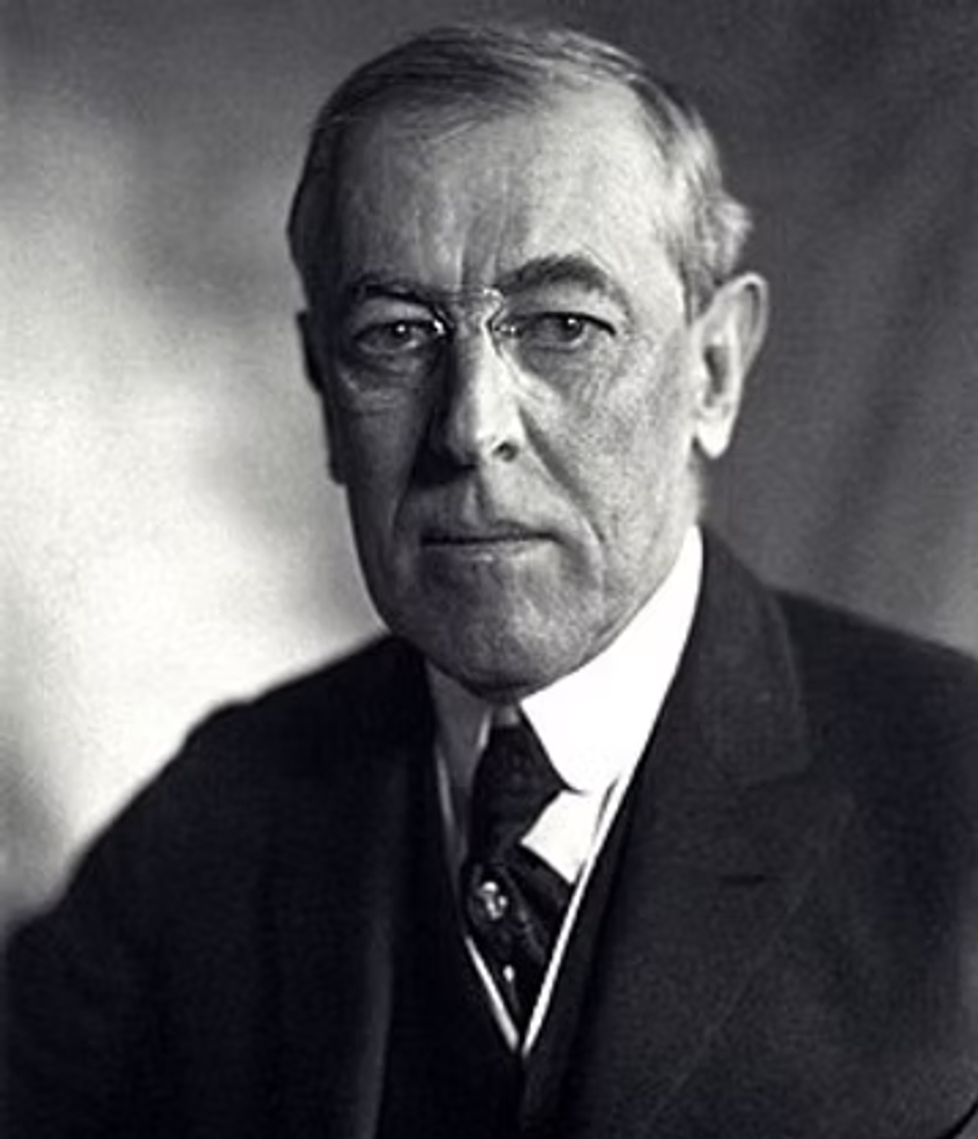 Black and white portrait photograph of Woodrow Wilson in formal business attire with a dark suit and tie, facing the camera.