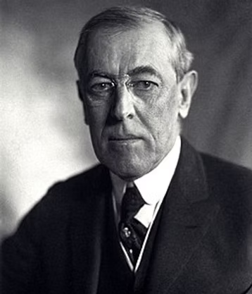 Black and white portrait photograph of Woodrow Wilson in formal business attire with a dark suit and tie, facing the camera.