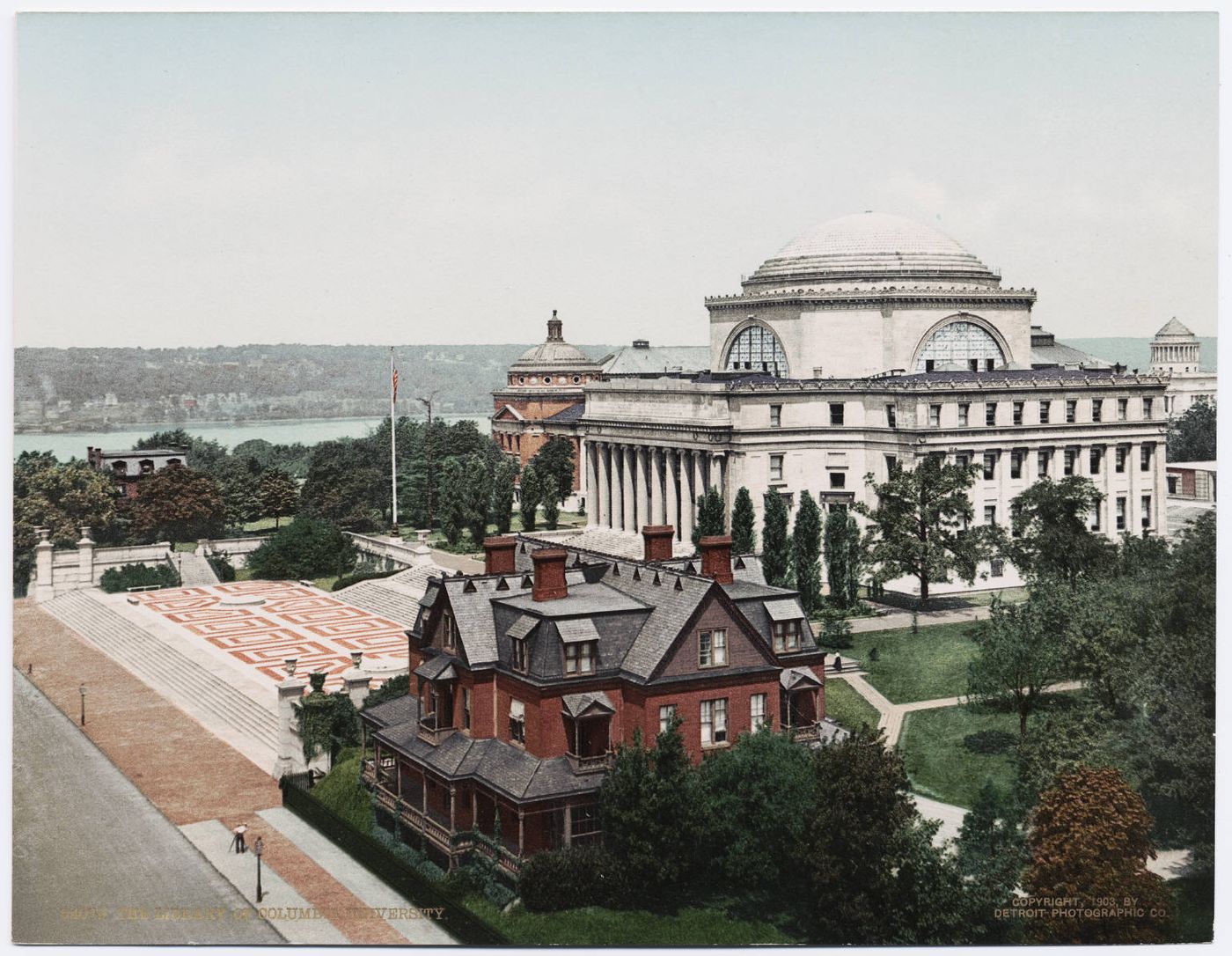 Color photochrom postcard of a university campus with a domed, columned library at center, a smaller brick hall at left, and a wooden house with porches in the foreground