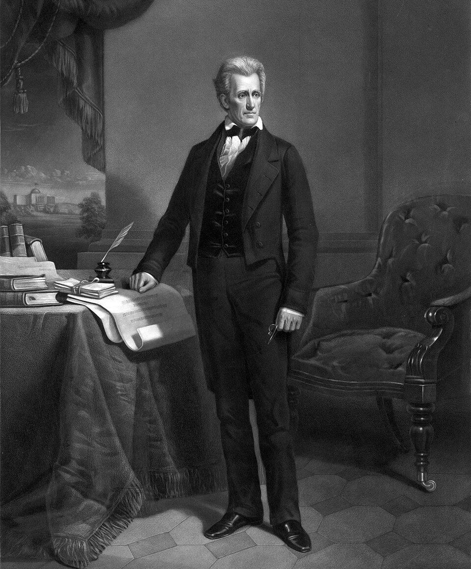 Formal portrait of a distinguished 19th-century Andrew Jackson in black suit standing at a desk with books and papers in an elegant interior.