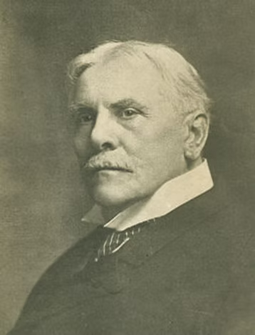 Portrait photograph of Cyrus Scofield with white hair and mustache wearing a dark suit and white collar, circa early 1900s.