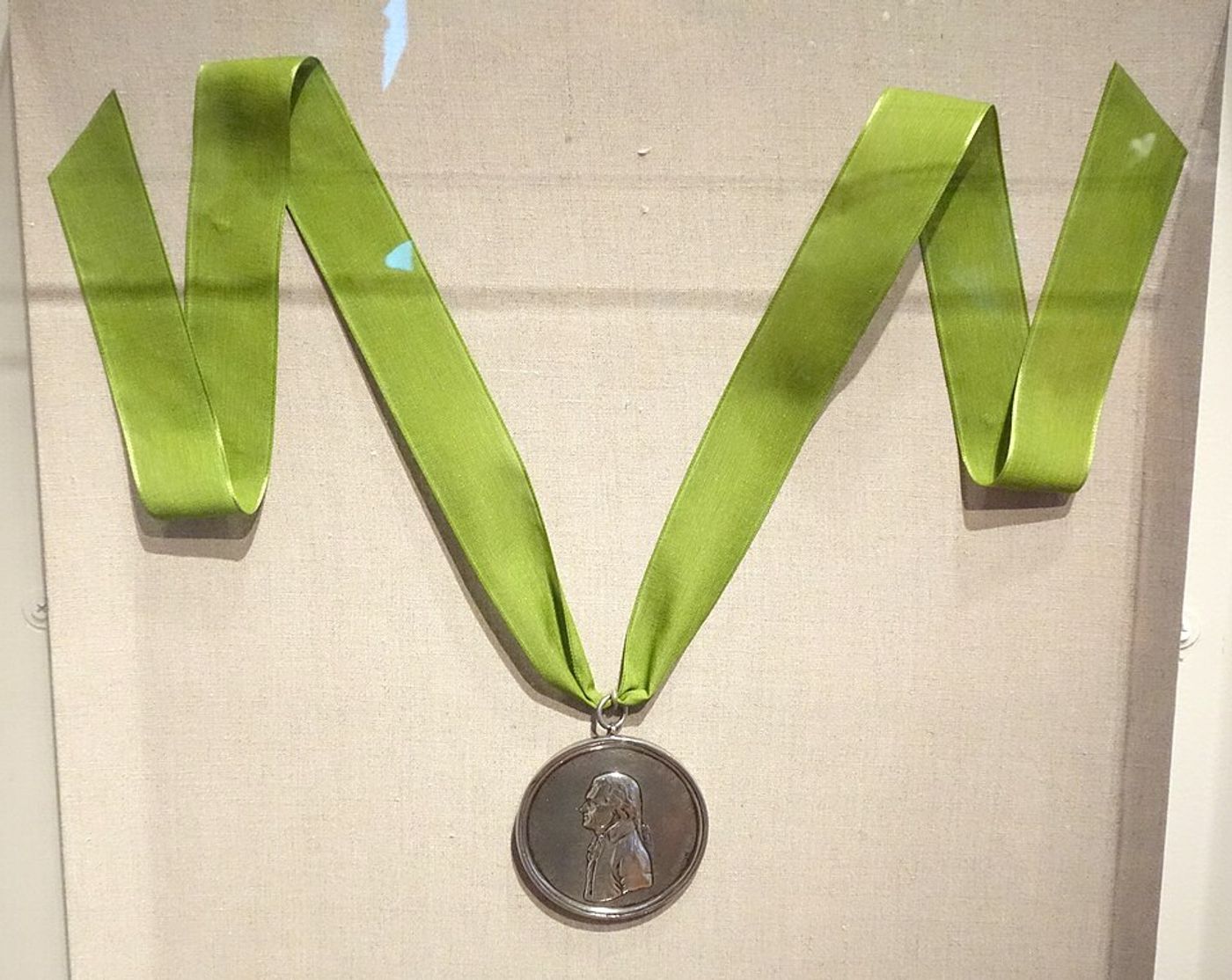 Silver Jefferson Indian peace medal on a green ribbon