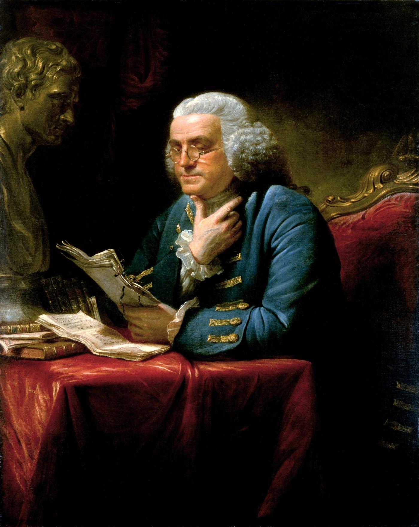 Oil portrait of Benjamin Franklin seated in a blue coat at a red-draped table, spectacles on, reading a sheaf of papers with his hand at his chin, a bust of Isaac Newton behind him