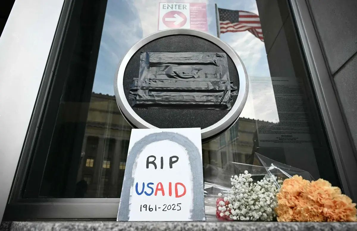 Tributes are placed beneath the covered seal of the United States Agency for International Development (USAID) at their headquarters in Washington, D.C., on February 7, the day that President Donald Trump called for the agency to be shuttered. July 1 marks the agency's official demise.