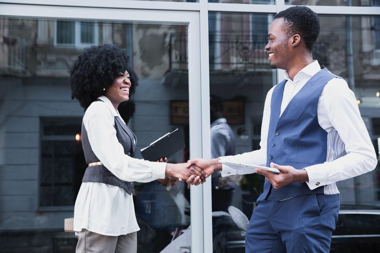 Two business partners shaking hands outside an office building