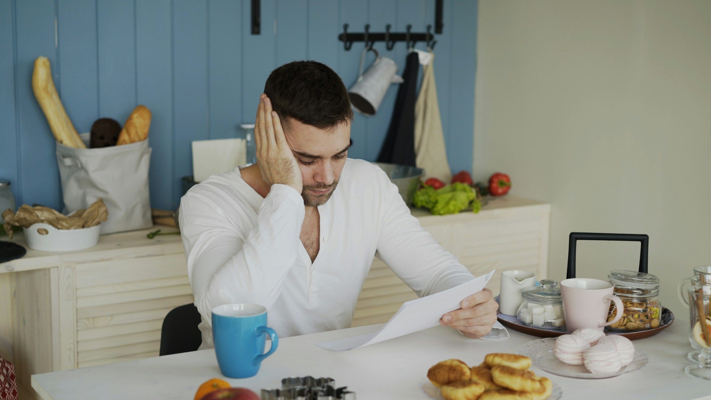 Hombre preocupado leyendo una carta en la mesa de su cocina, un momento que conocen muchos trabajadores que sufren represalias
