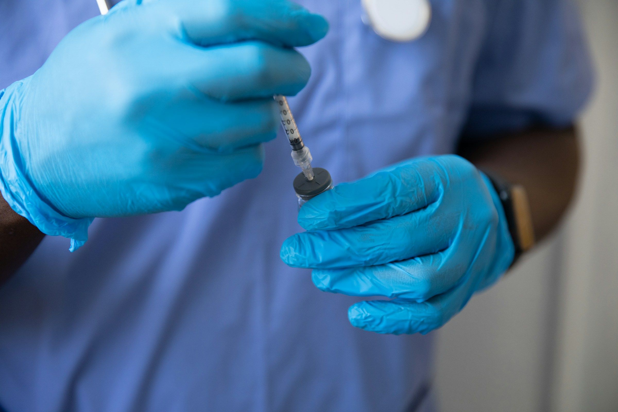 Gloved hands drawing medicine into a syringe, the sharps work behind needlestick claims a healthcare worker injury attorney handles