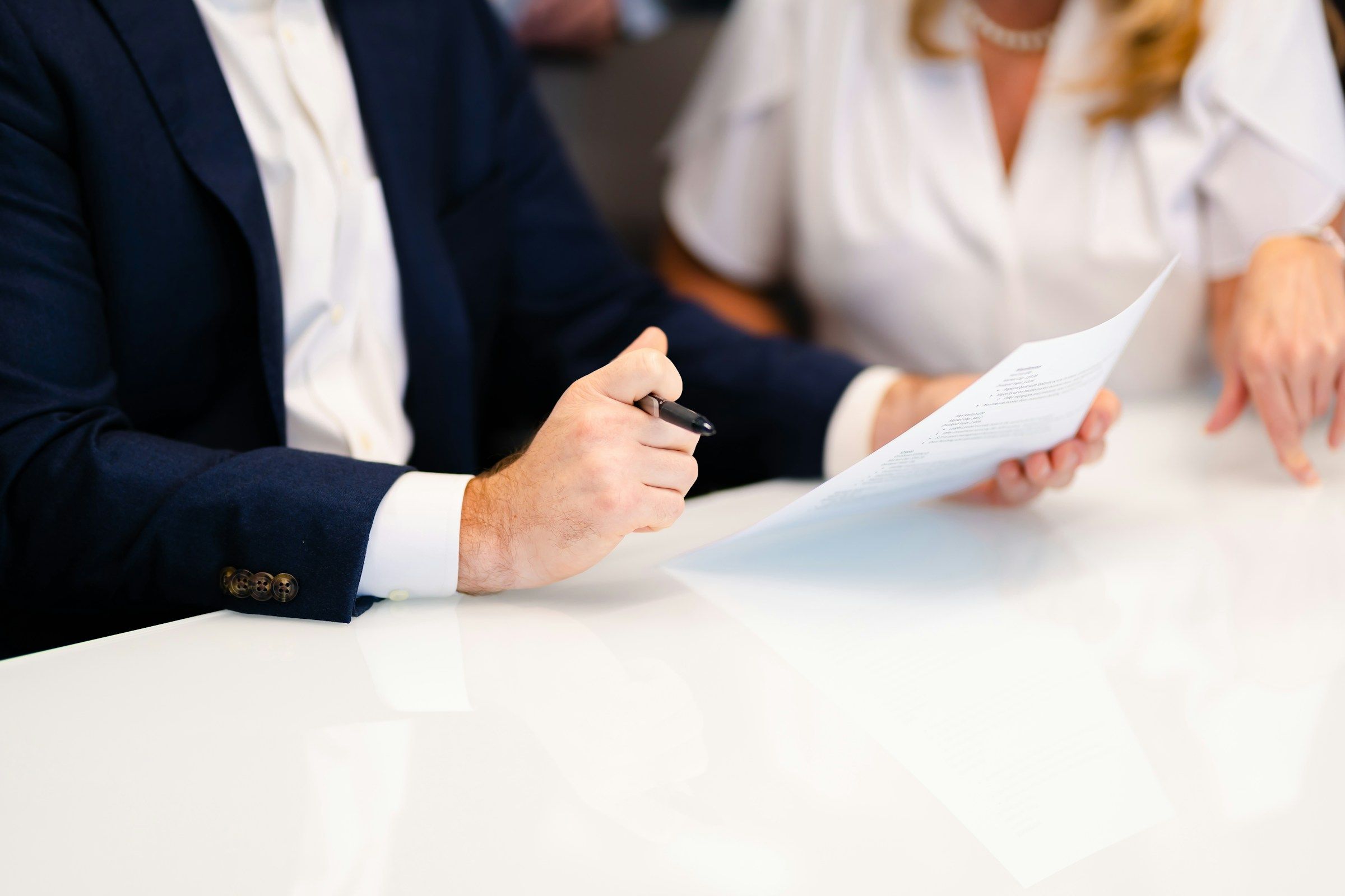 Two people at a white table going over a printed document, pen in hand, the way a workers’ comp settlement offer should be reviewed