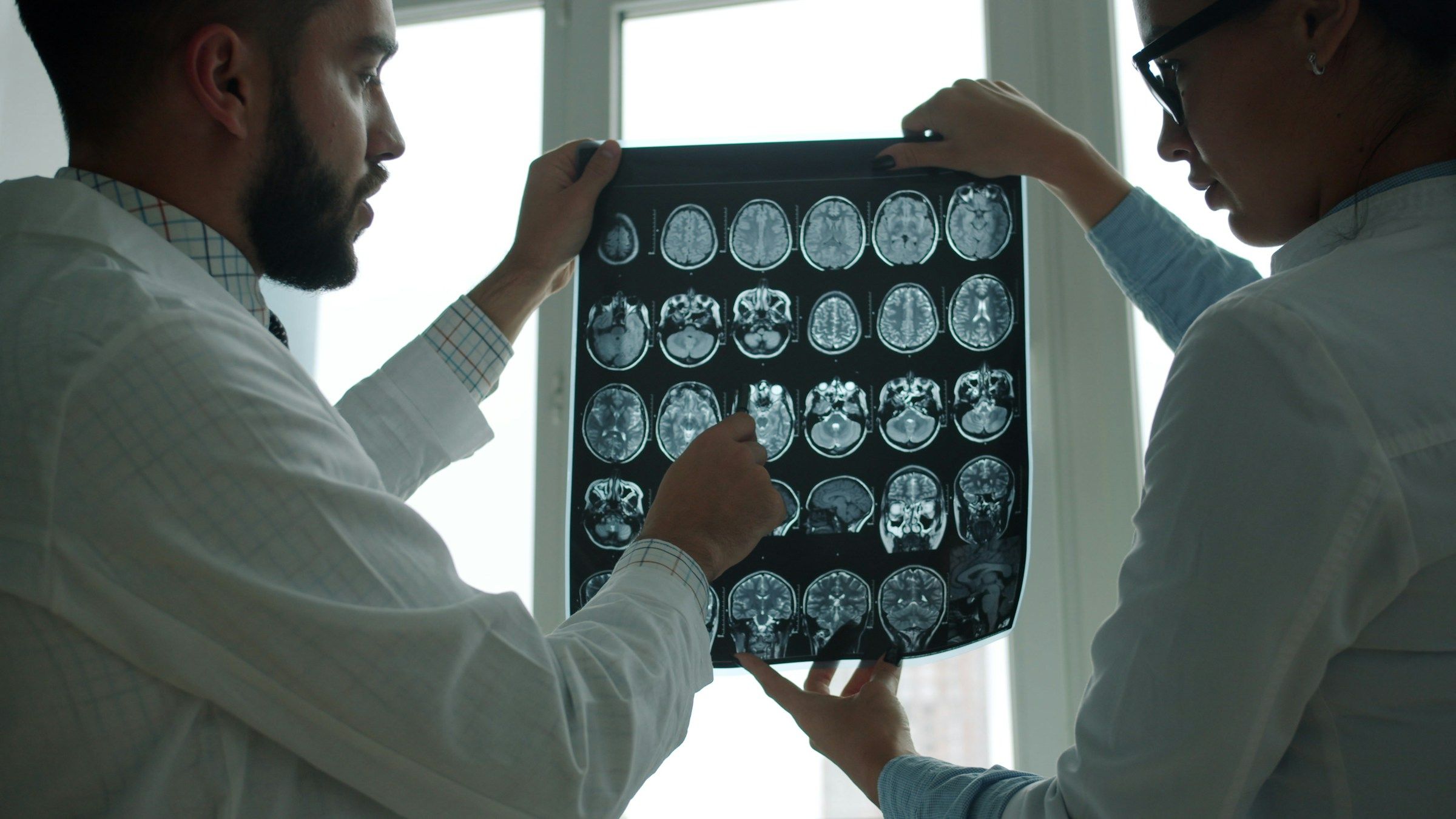 Dos médicos revisando imágenes de resonancia del cerebro, parte de los estudios que puede requerir un reclamo por lesión cerebral