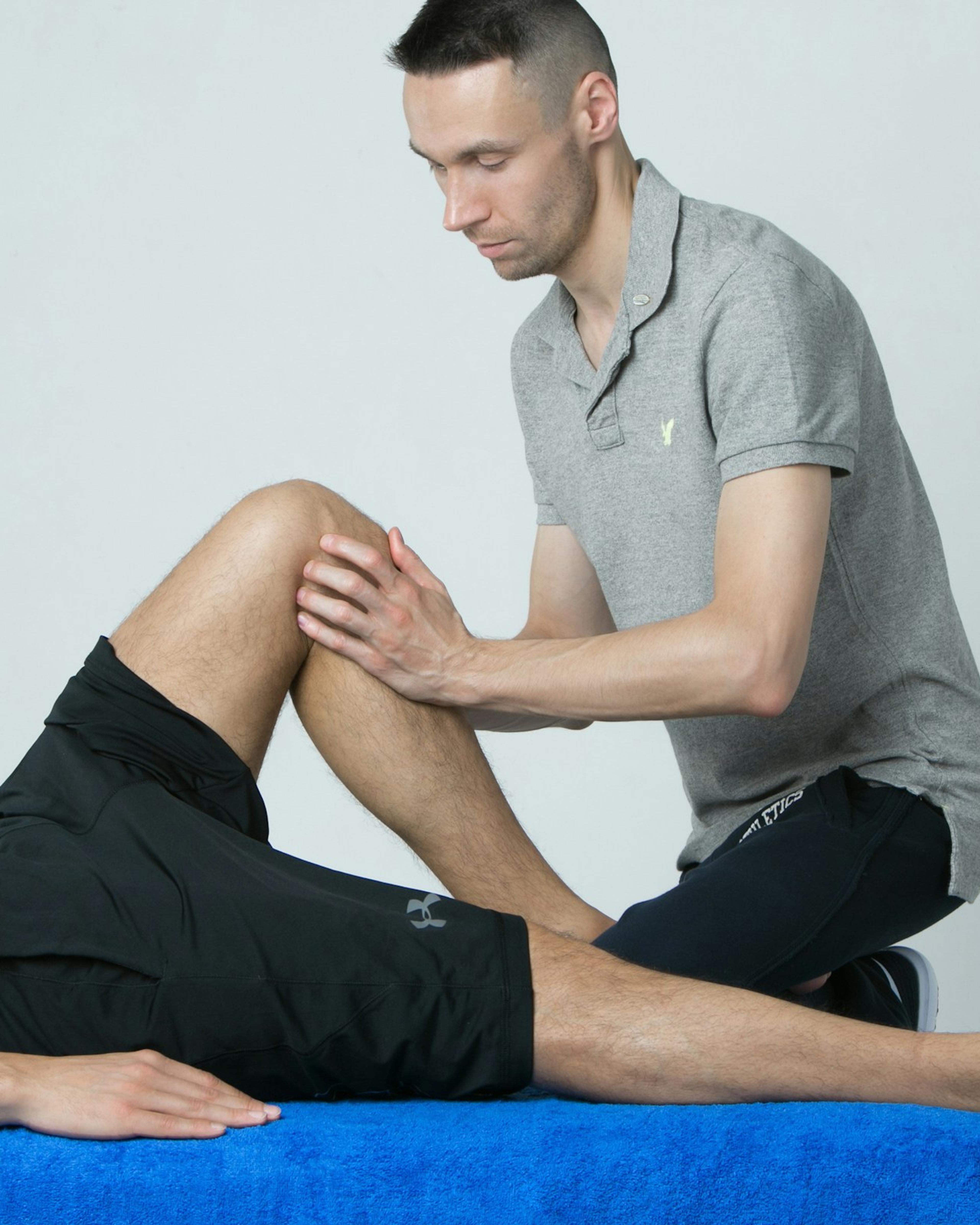 Practitioner examining a patient’s bent knee, the kind of evaluation that comes before knee surgery in a workers’ comp claim