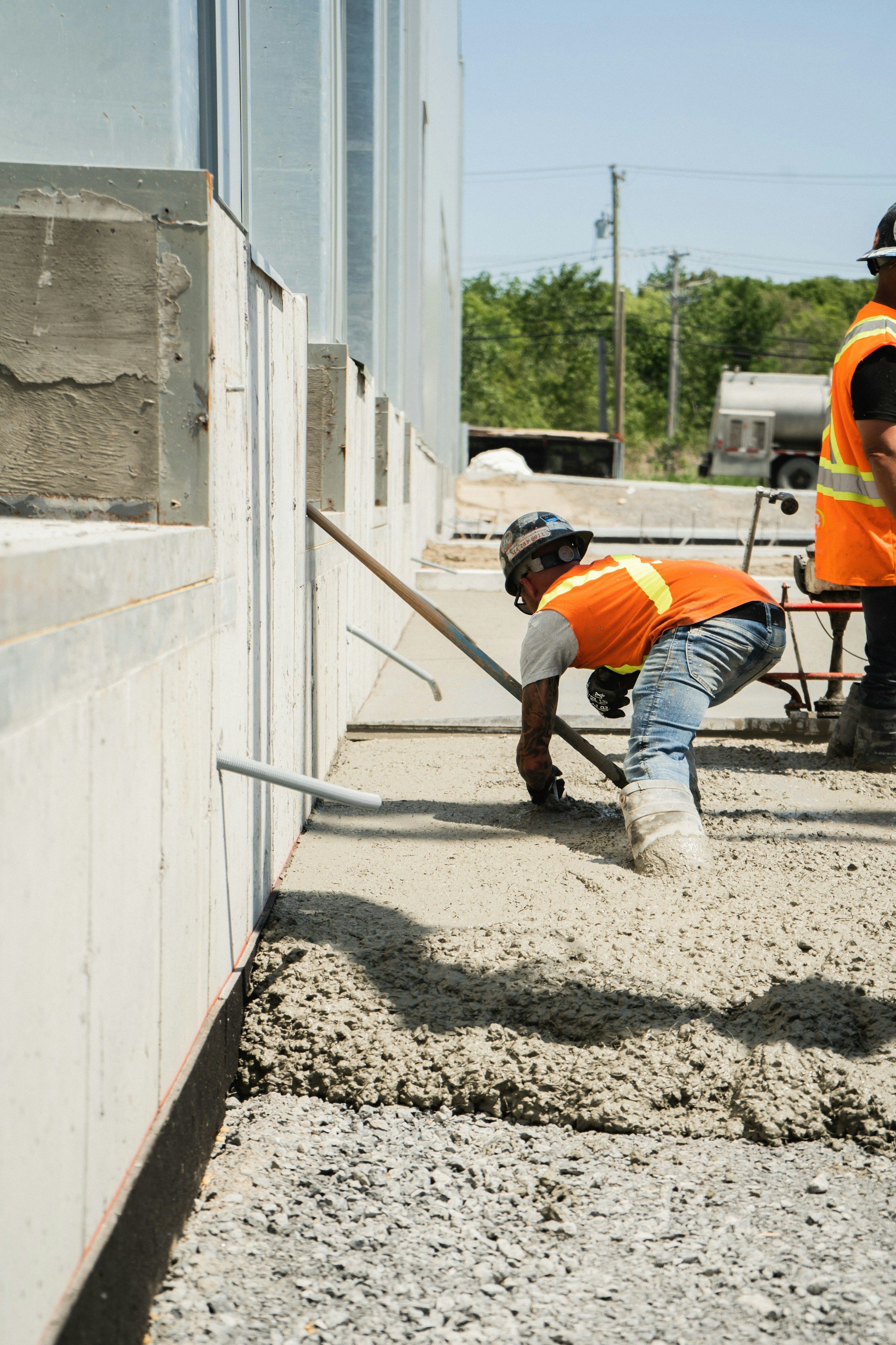 Concrete worker crouching low to spread a fresh pour, the squatting and kneeling that can lead to a meniscus tear