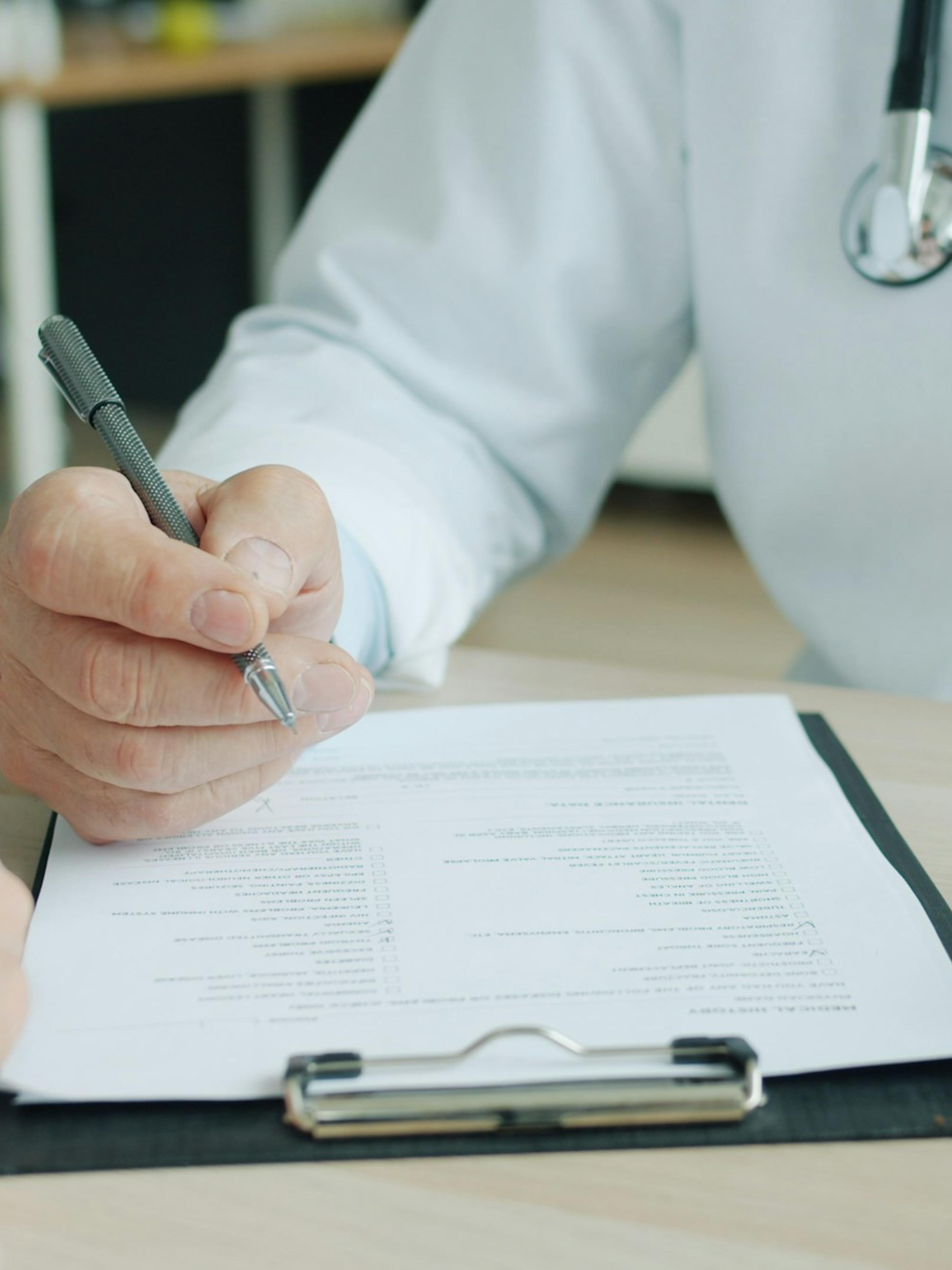 Médico escribiendo en un formulario frente a un paciente, el tipo de informe en que se basa una calificación de incapacidad permanente