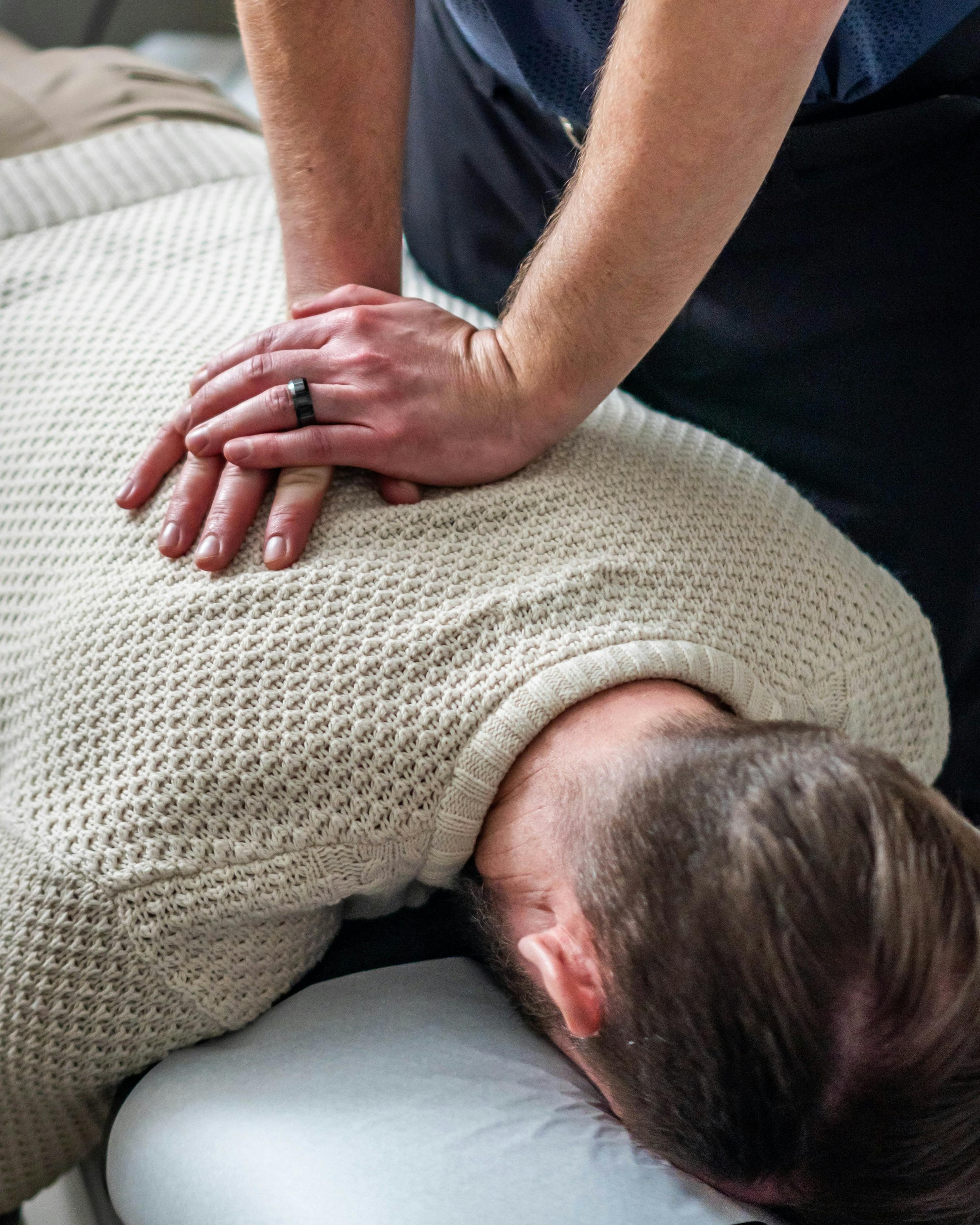 Chiropractor pressing on a patient’s upper back, one of the treatments workers’ comp can cover for a back injury