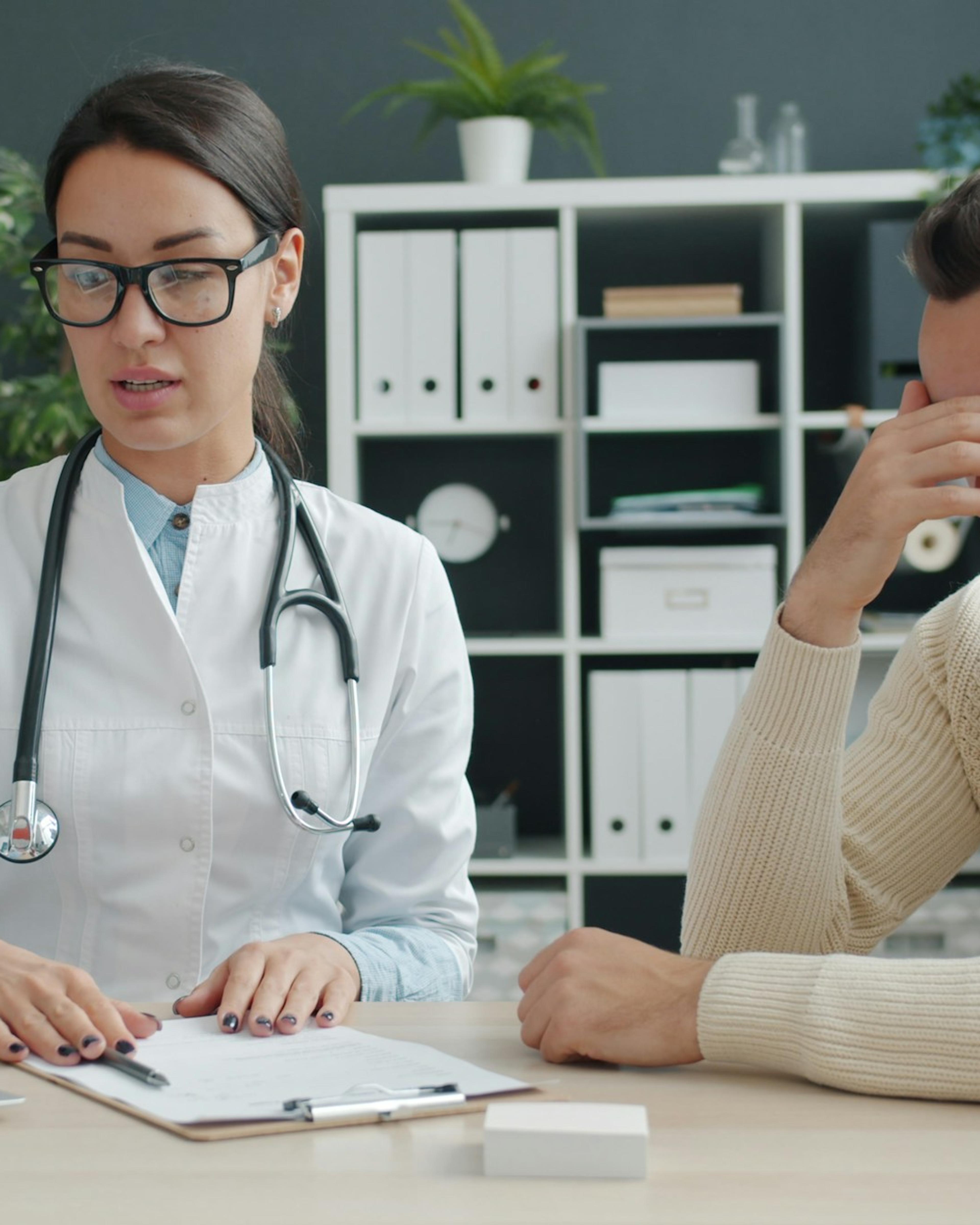 Médica explicando resultados a un paciente frustrado, una consulta que puede terminar en una calificación baja o una disputa con el QME