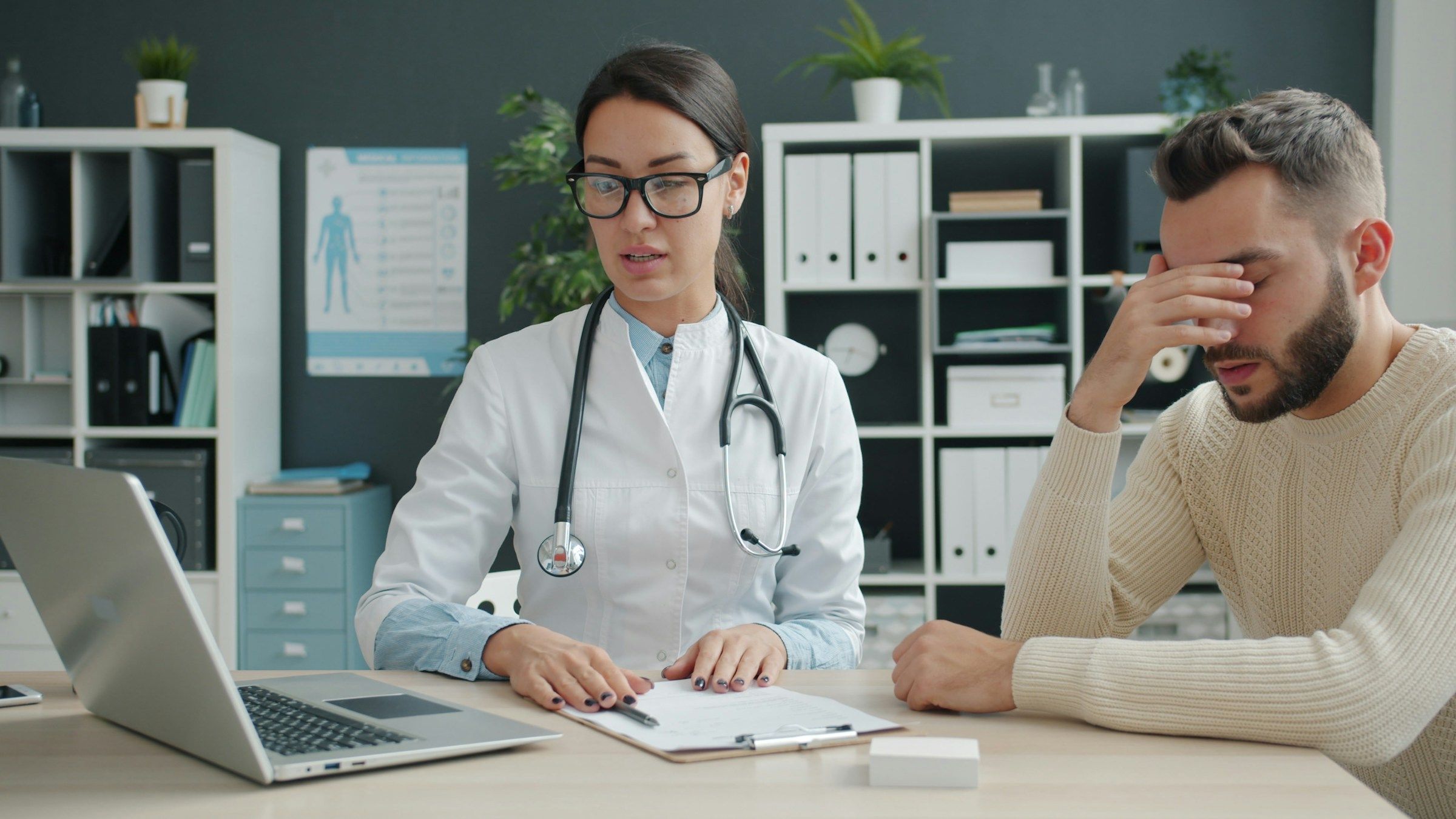 Doctor explaining exam results to a frustrated patient, the kind of visit that can end in a low PD rating or a QME dispute