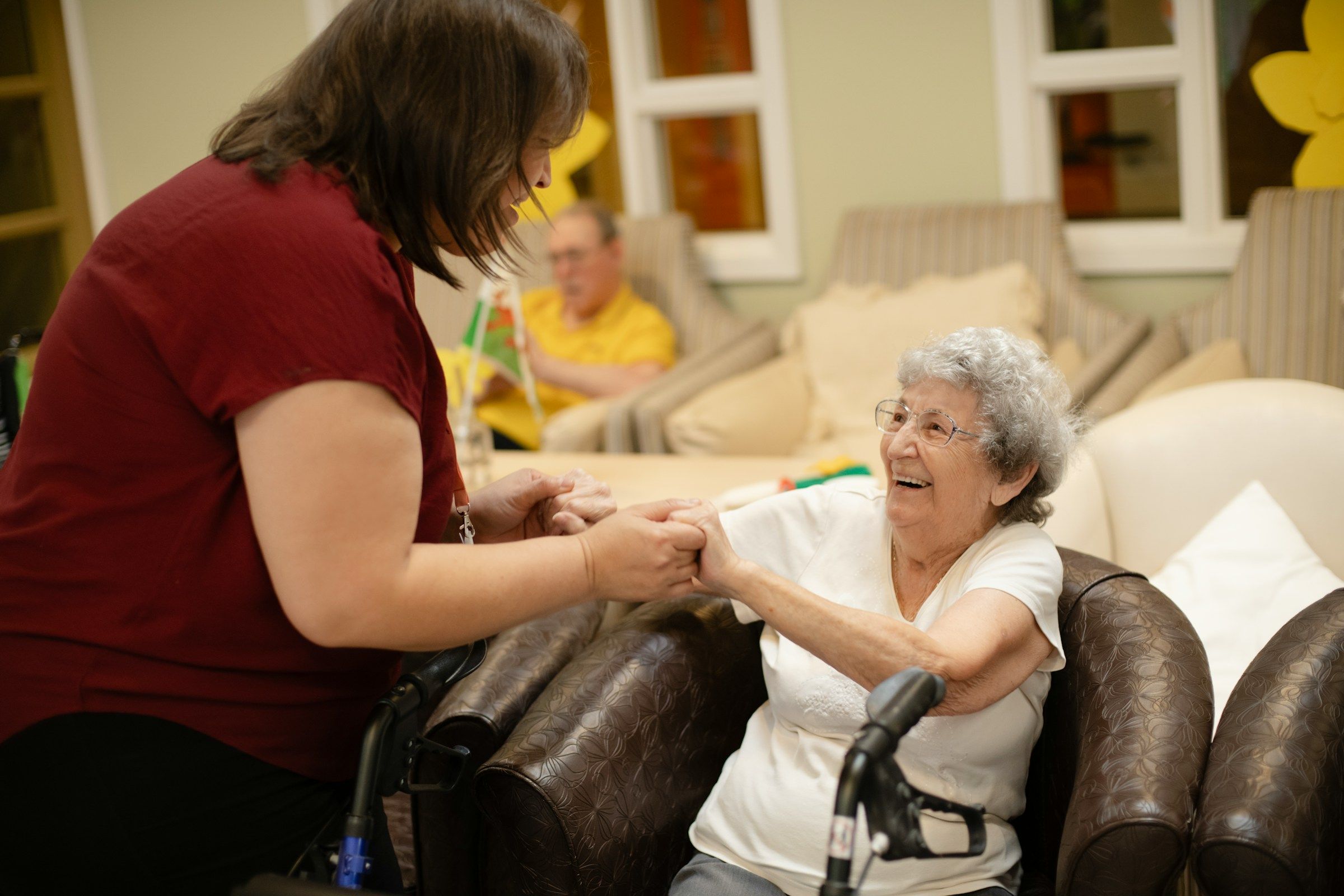 Caregiver helping an older woman stand up from an armchair, the kind of lift behind many CNA injury and healthcare worker claims
