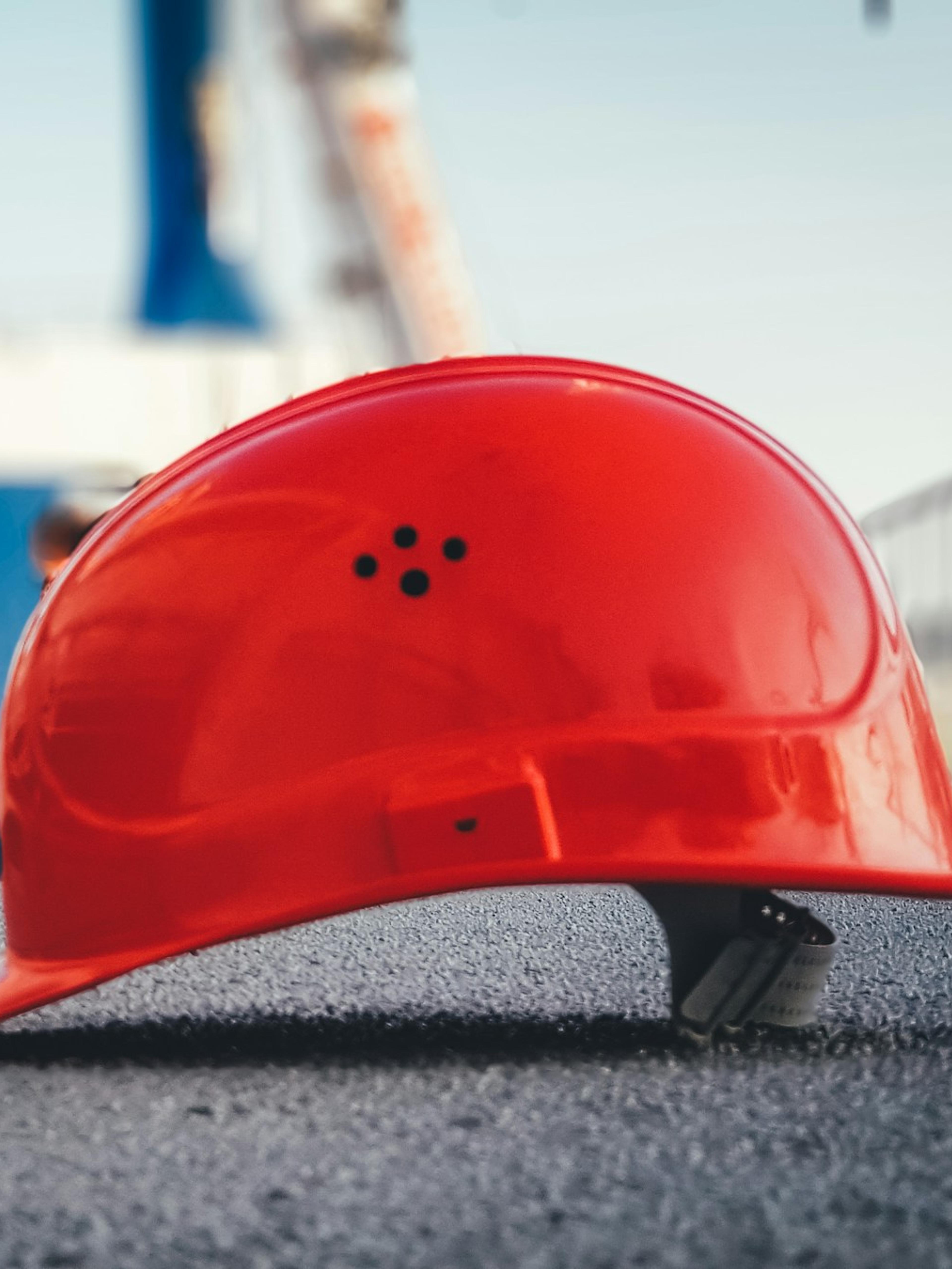 Red hard hat on the pavement at a construction site, a reminder of the risks behind a head injury at work