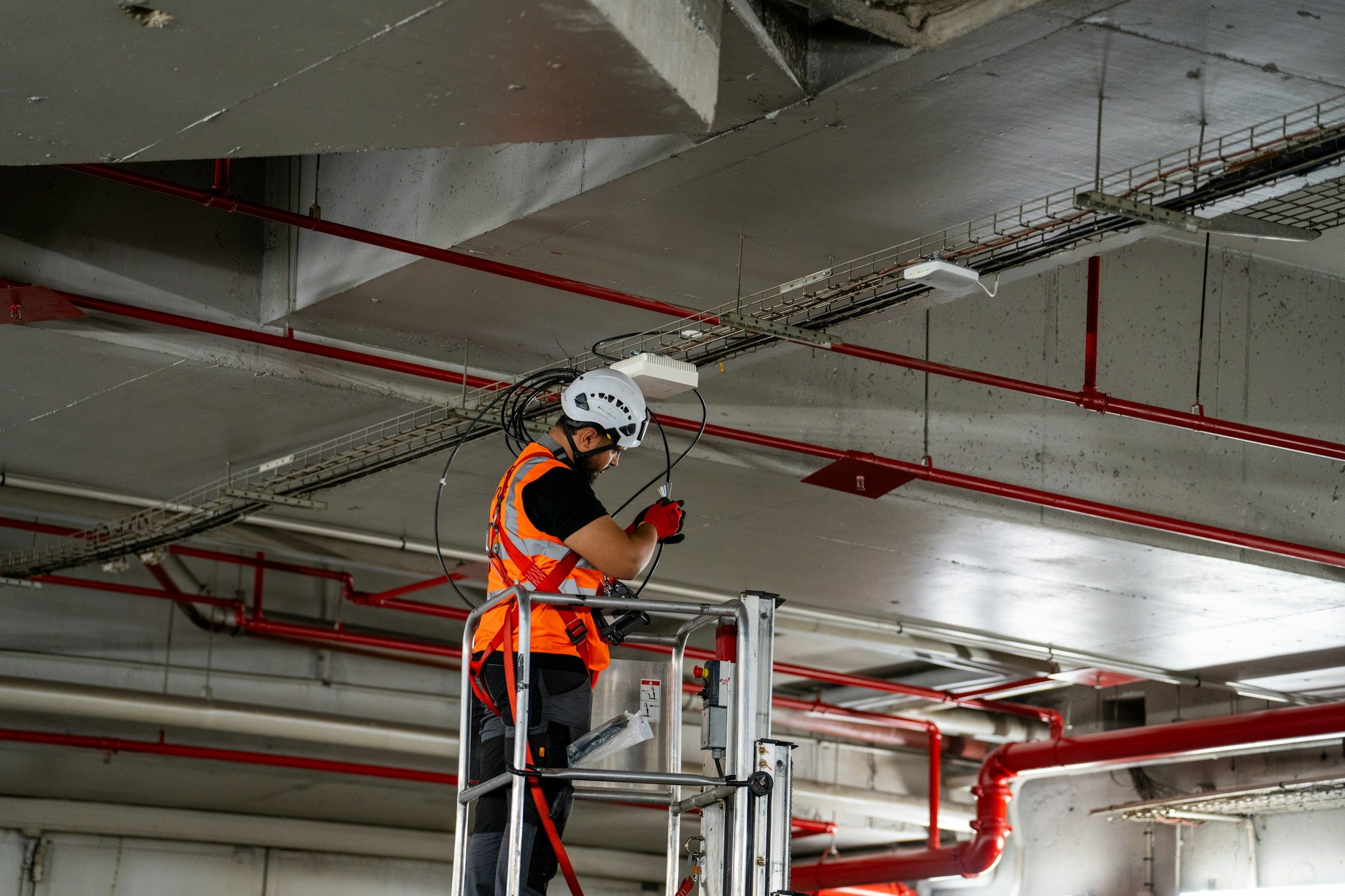 Trabajador en una plataforma elevadora instalando cables en el techo, el esfuerzo detrás de muchos reclamos por lesión de hombro