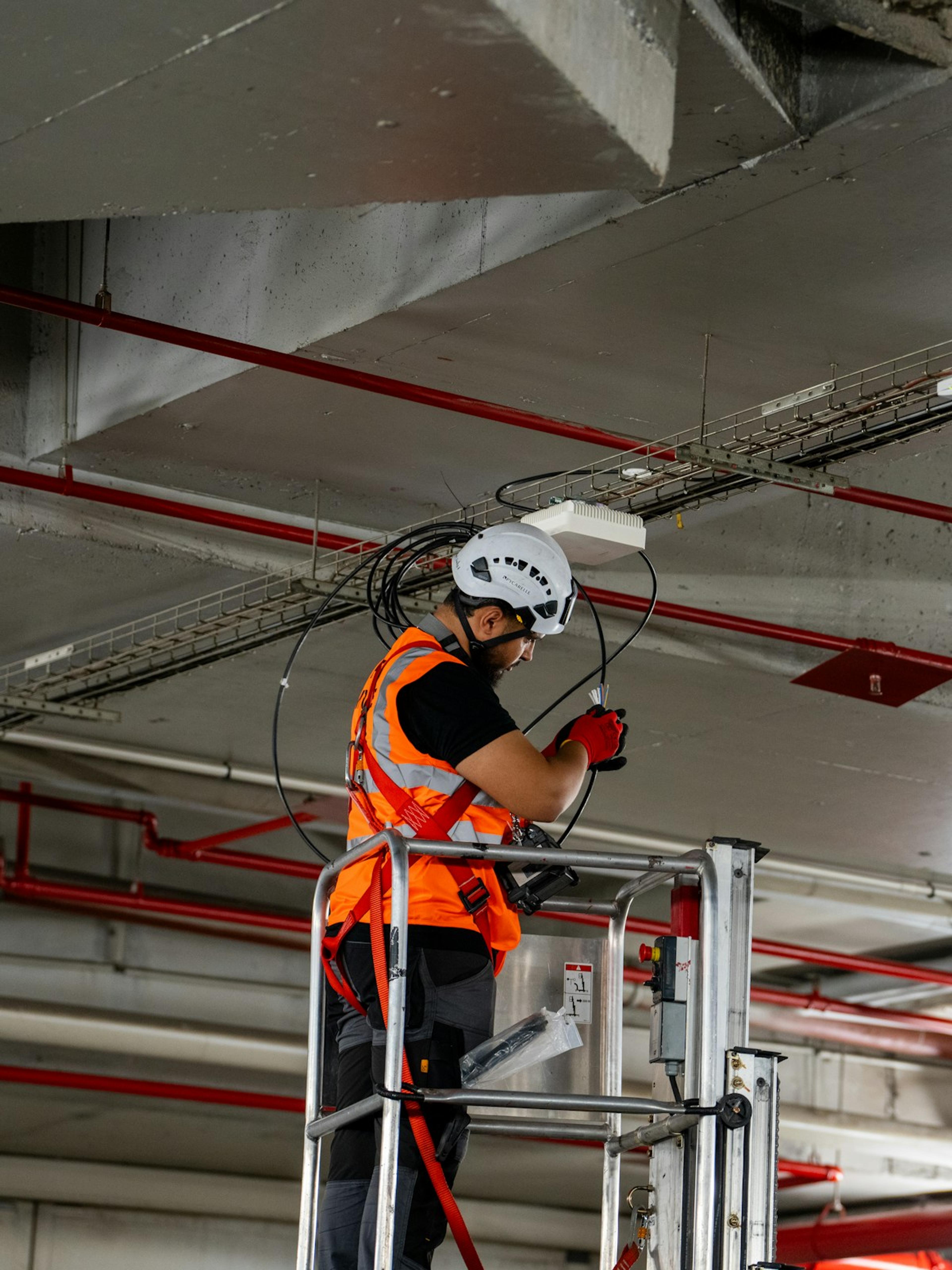 Trabajador en una plataforma elevadora instalando cables en el techo, el esfuerzo detrás de muchos reclamos por lesión de hombro