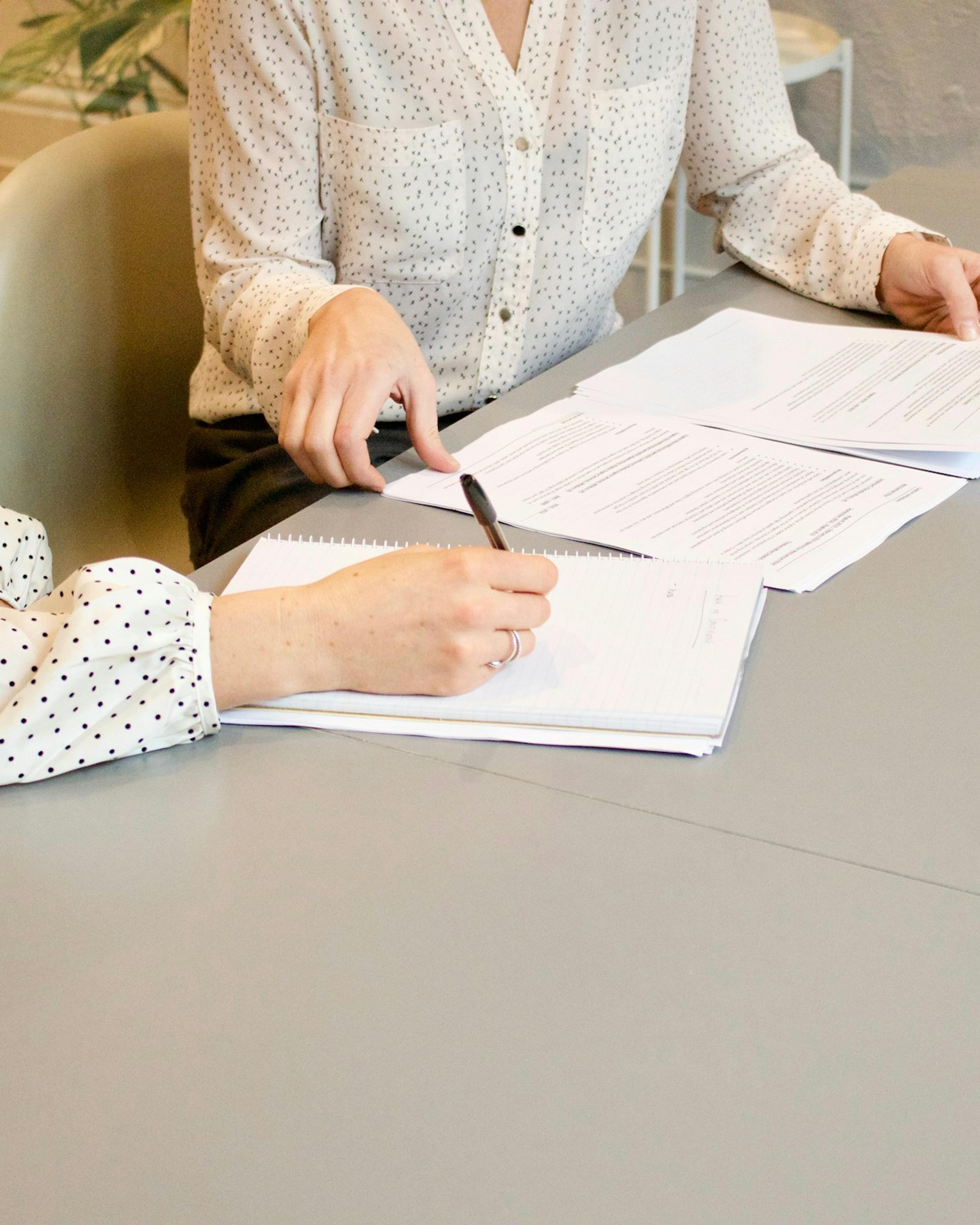 Two people reviewing and signing documents at a table