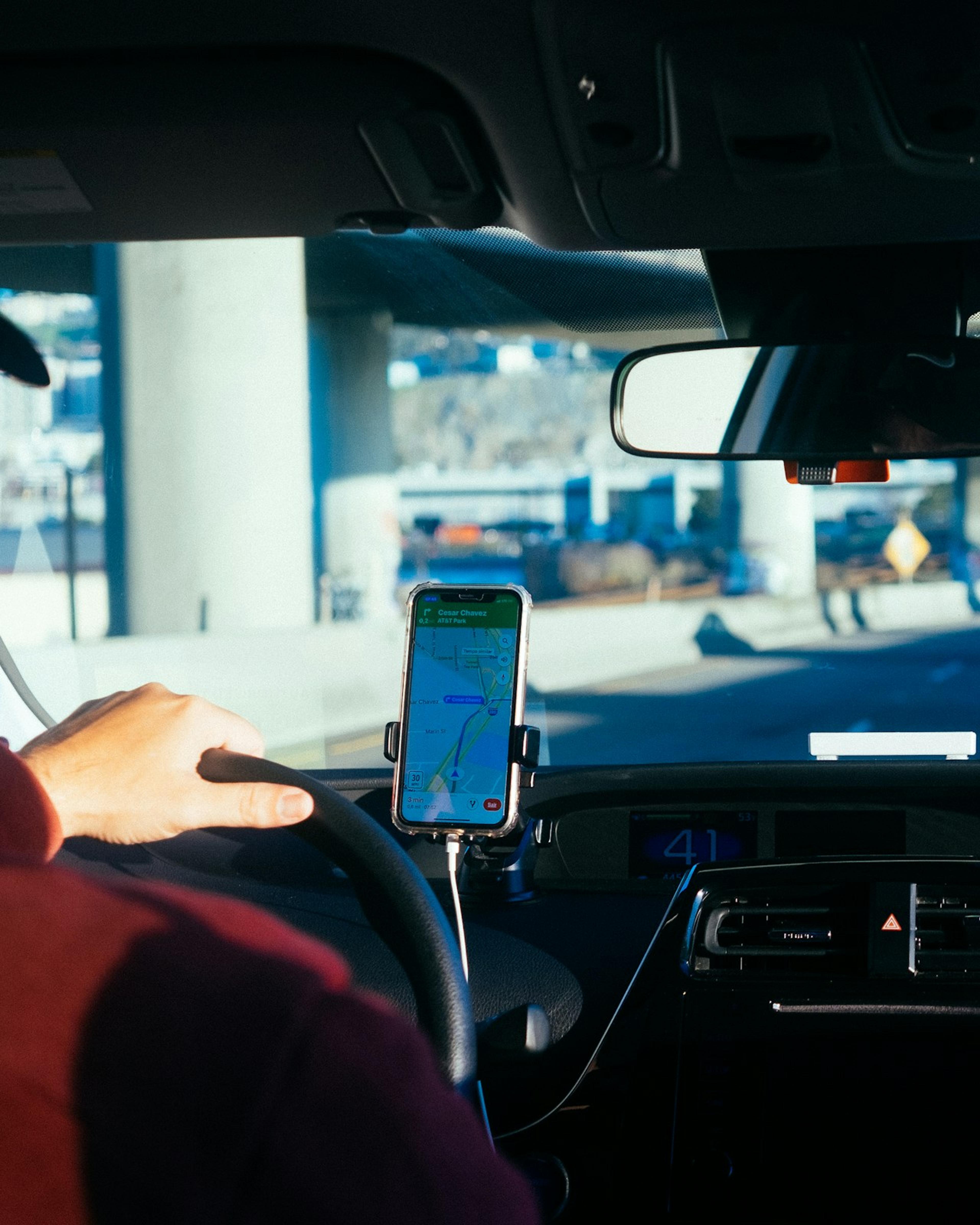 App-based driver following a phone navigation app on the dashboard; long hours on the road are part of many courier injury claims