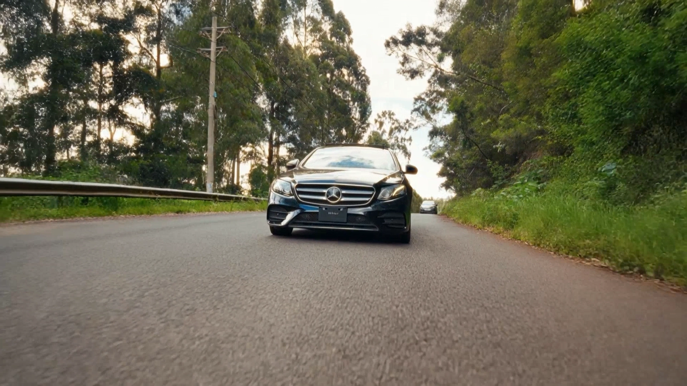 Black Mercedes driving toward camera on an open road
