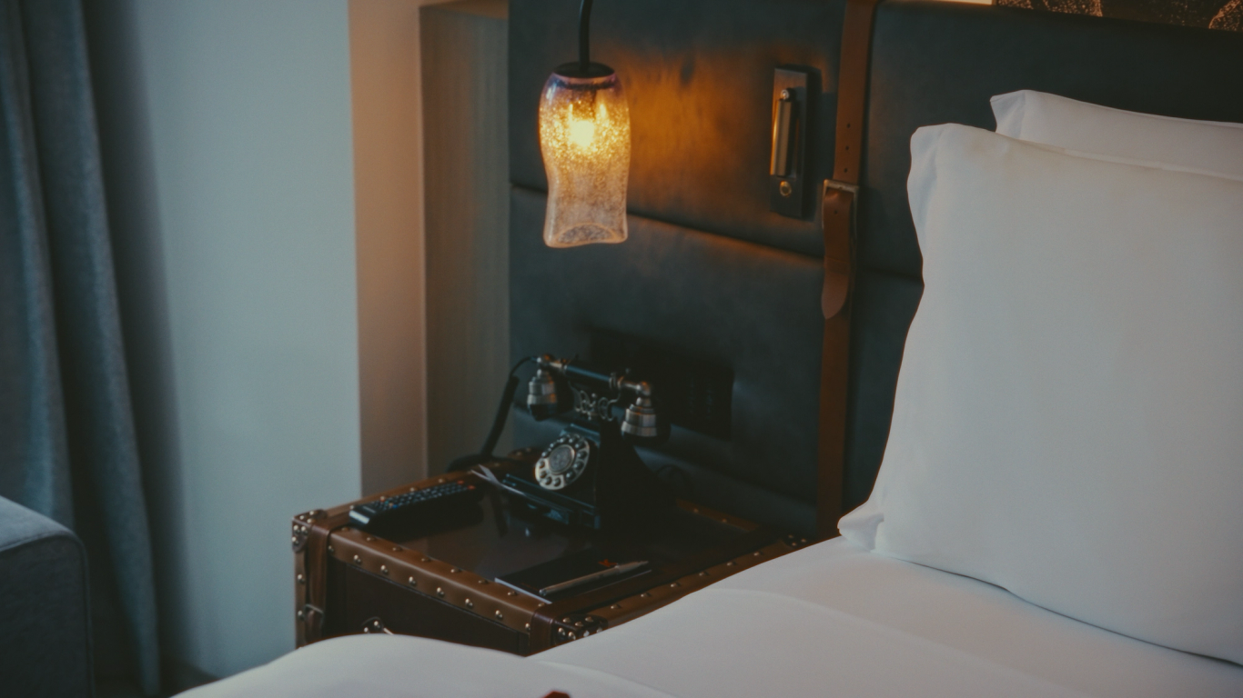 Bedside detail with a vintage telephone and warm pendant light
