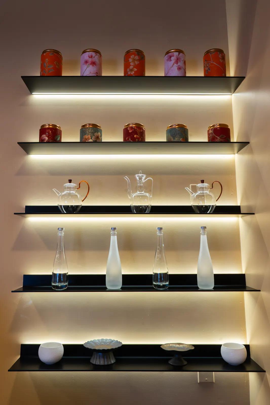 Tea tins and glass pots, shelved and lit