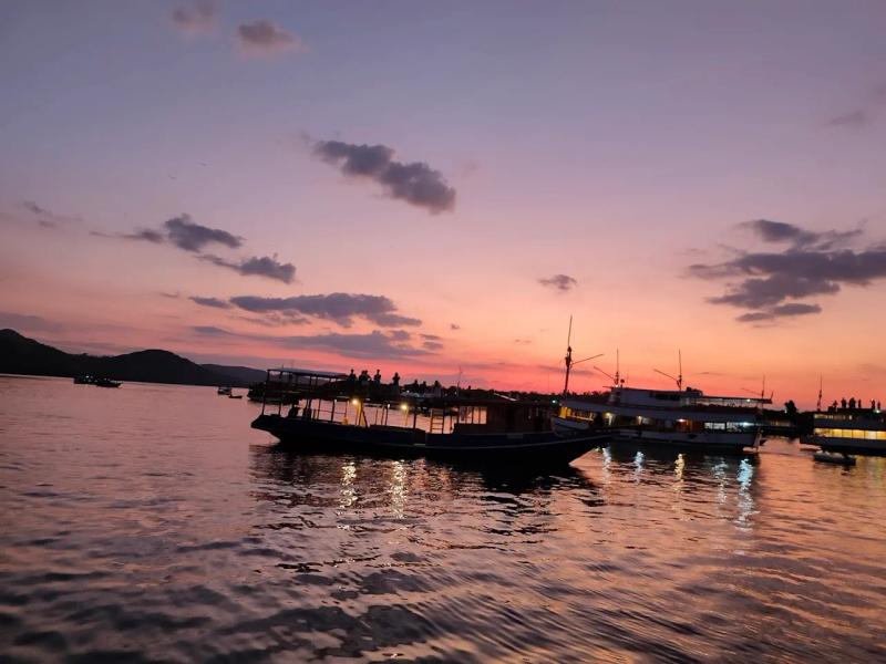 Traditional wooden Phinisi boats anchored in Labuan Bajo at sunset