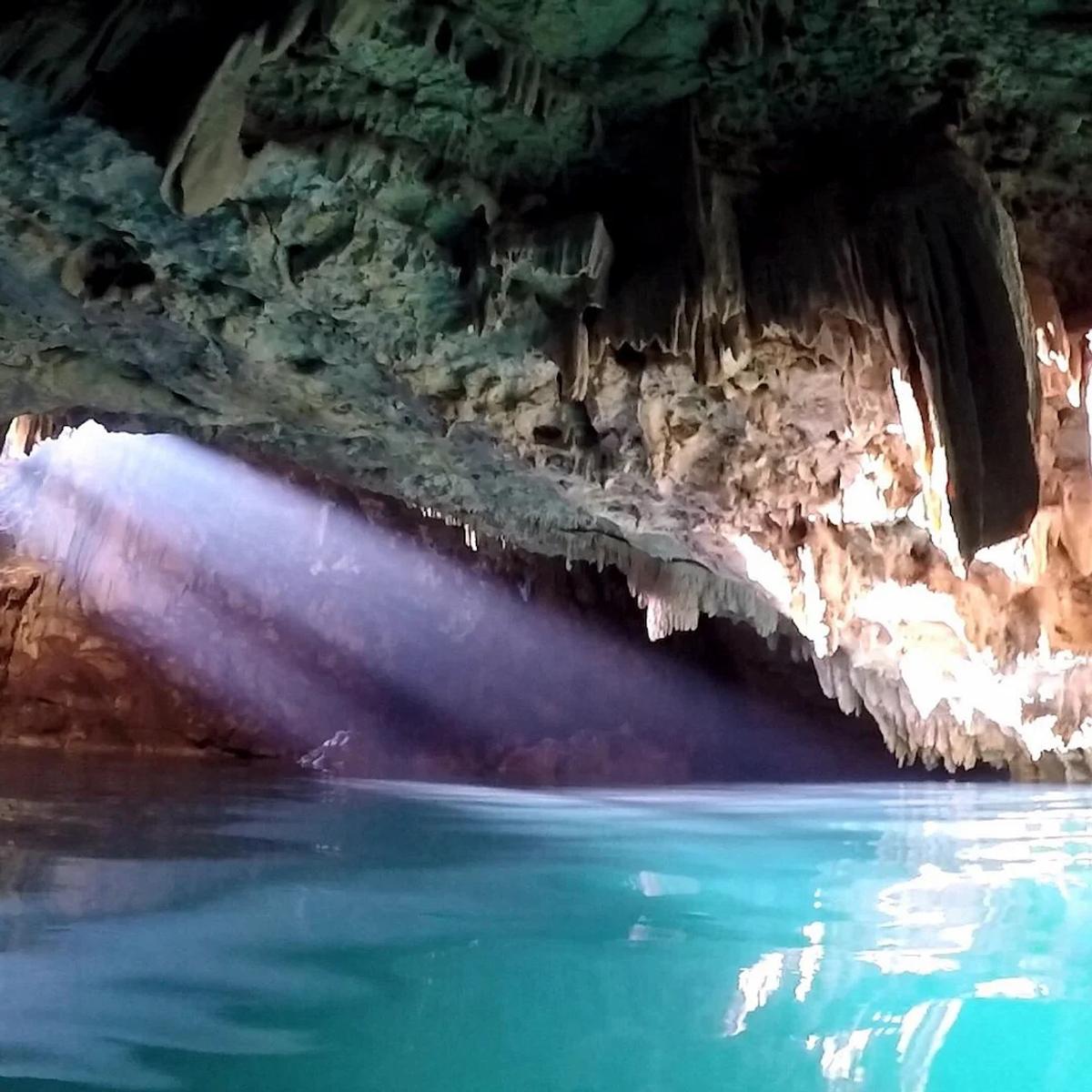 Sinar matahari menembus mulut Goa Rangko dan menyinari air biru toska di dalam gua Labuan Bajo