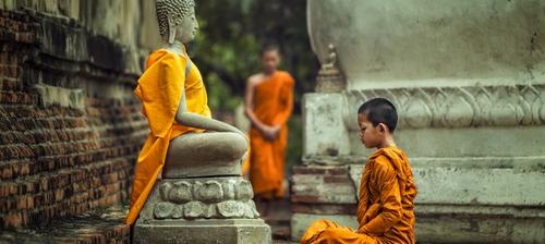 giovane monaco tibetano prega statua di buddha