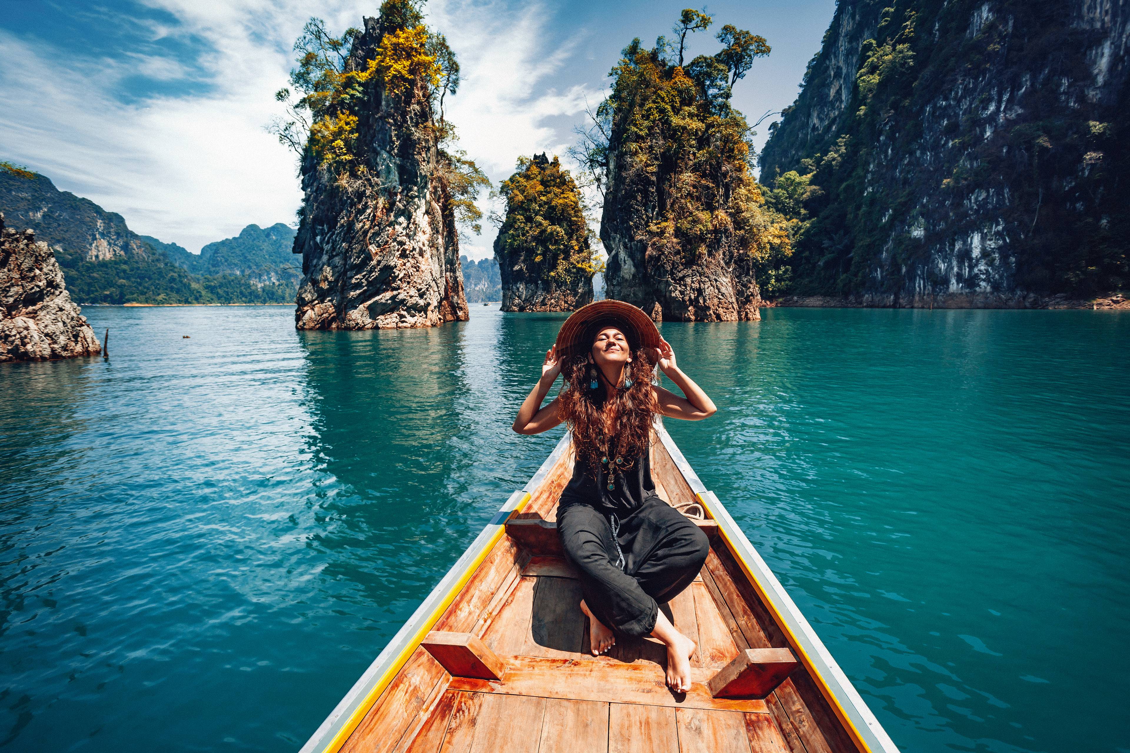 donna con cappello su barca rocce cheow lan thailandia
