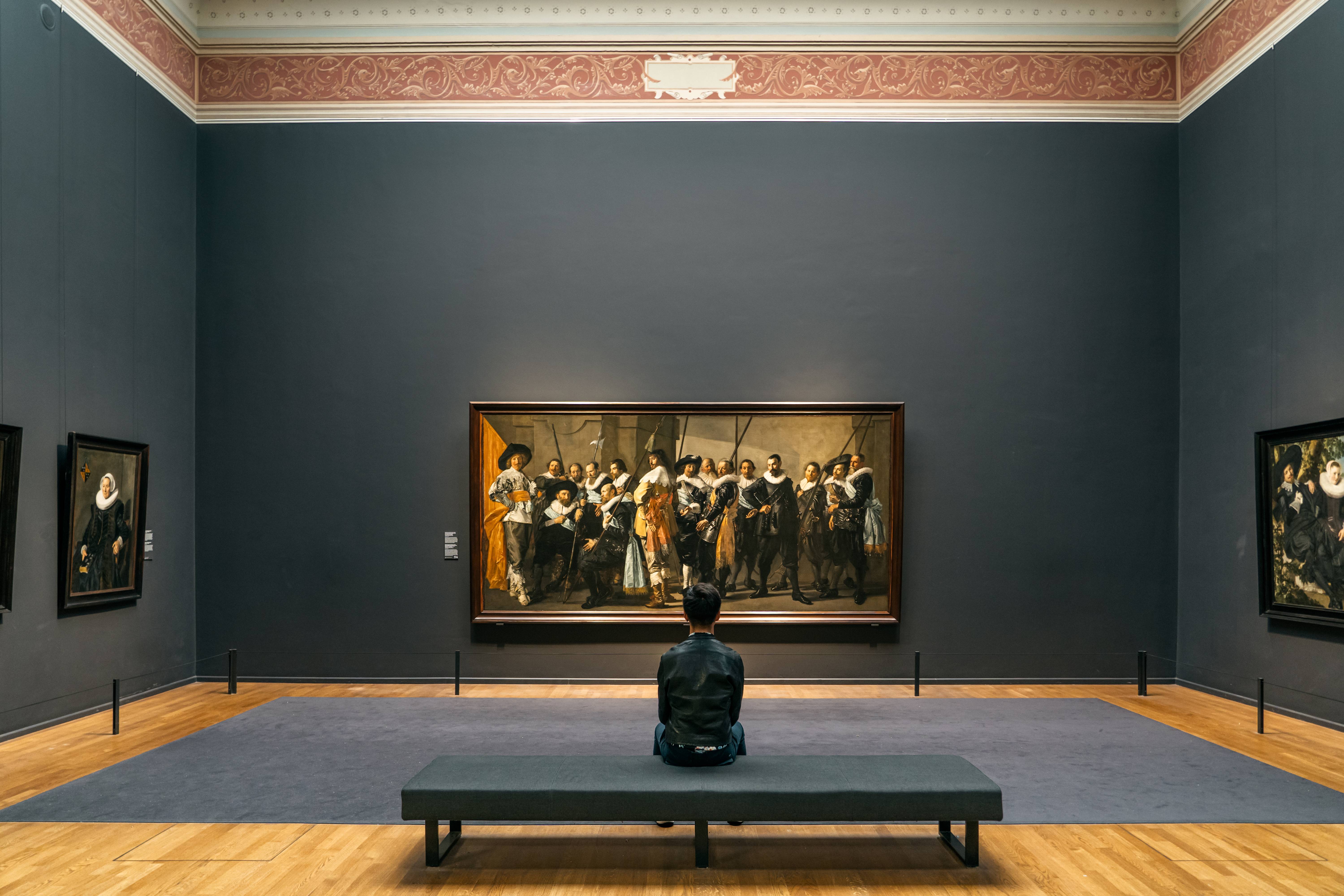 uomo seduto a guardare quadro in un museo