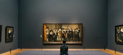 uomo seduto a guardare quadro in un museo