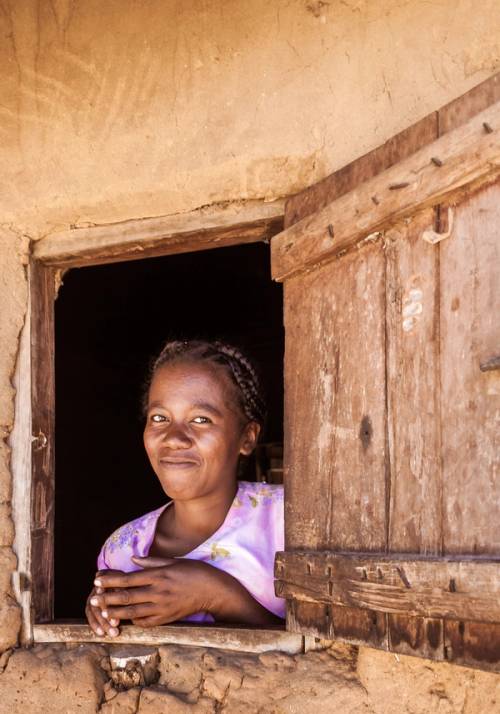 bambina malgascia sorride dalla finestra di casa sua in madagascar