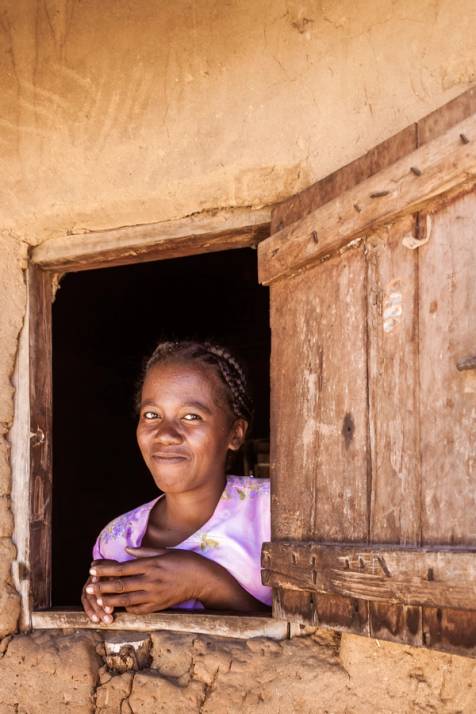bambina malgascia sorride dalla finestra di casa sua in madagascar
