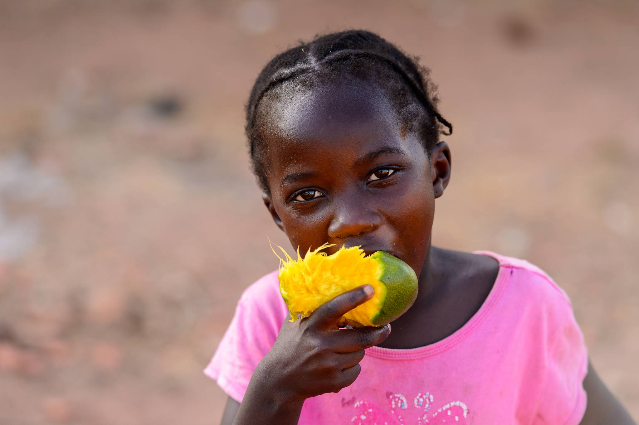 African girl eating mango with her hands