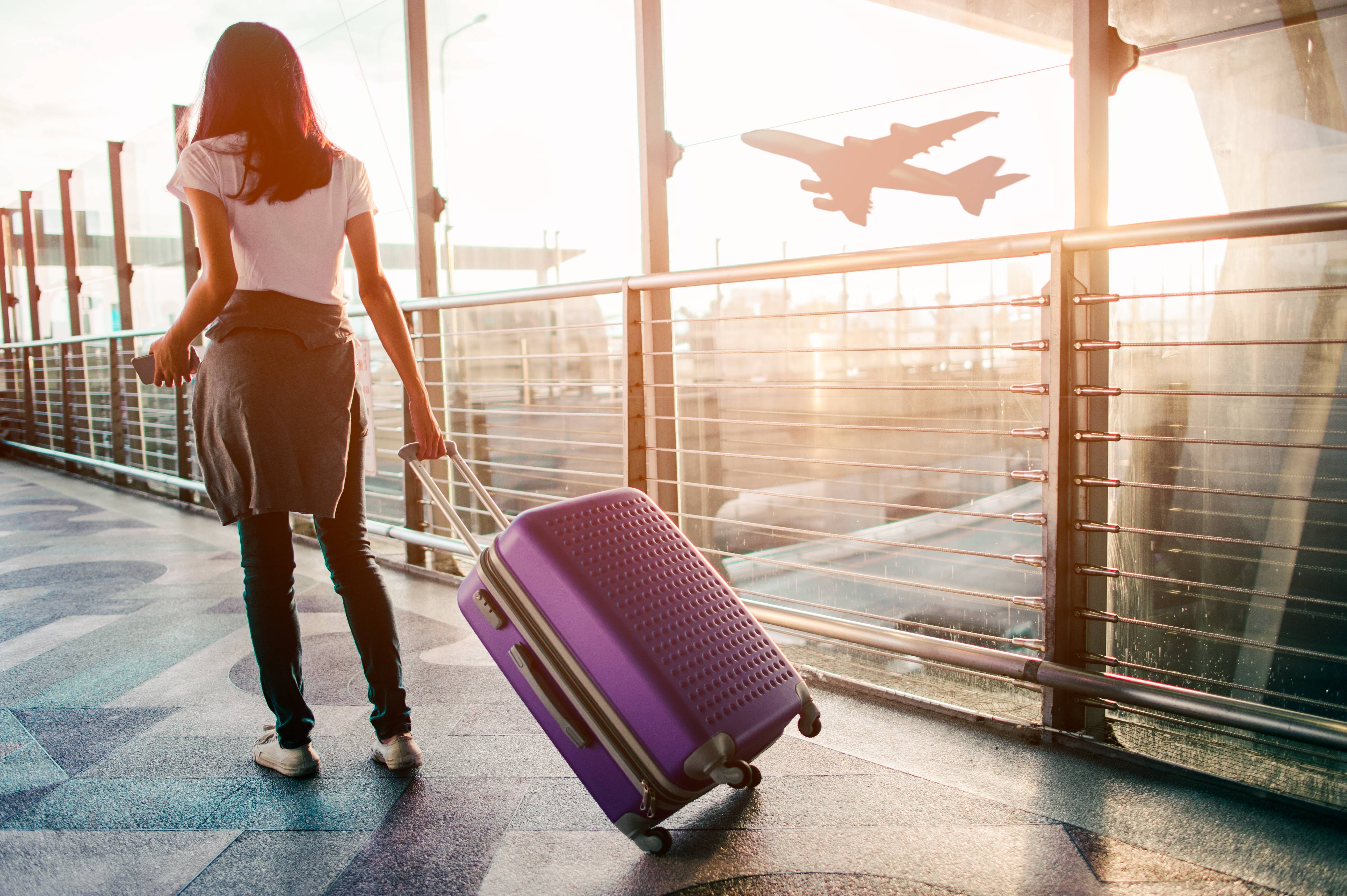 donna con valigia viola in aeroporto aereo in volo sullo sfondo