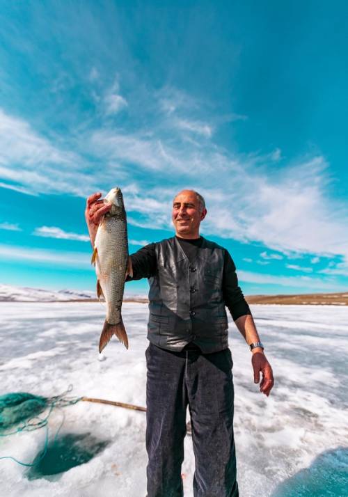uomo pesca pesce in un lago ghiacciato