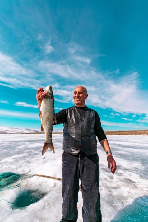 uomo pesca pesce in un lago ghiacciato