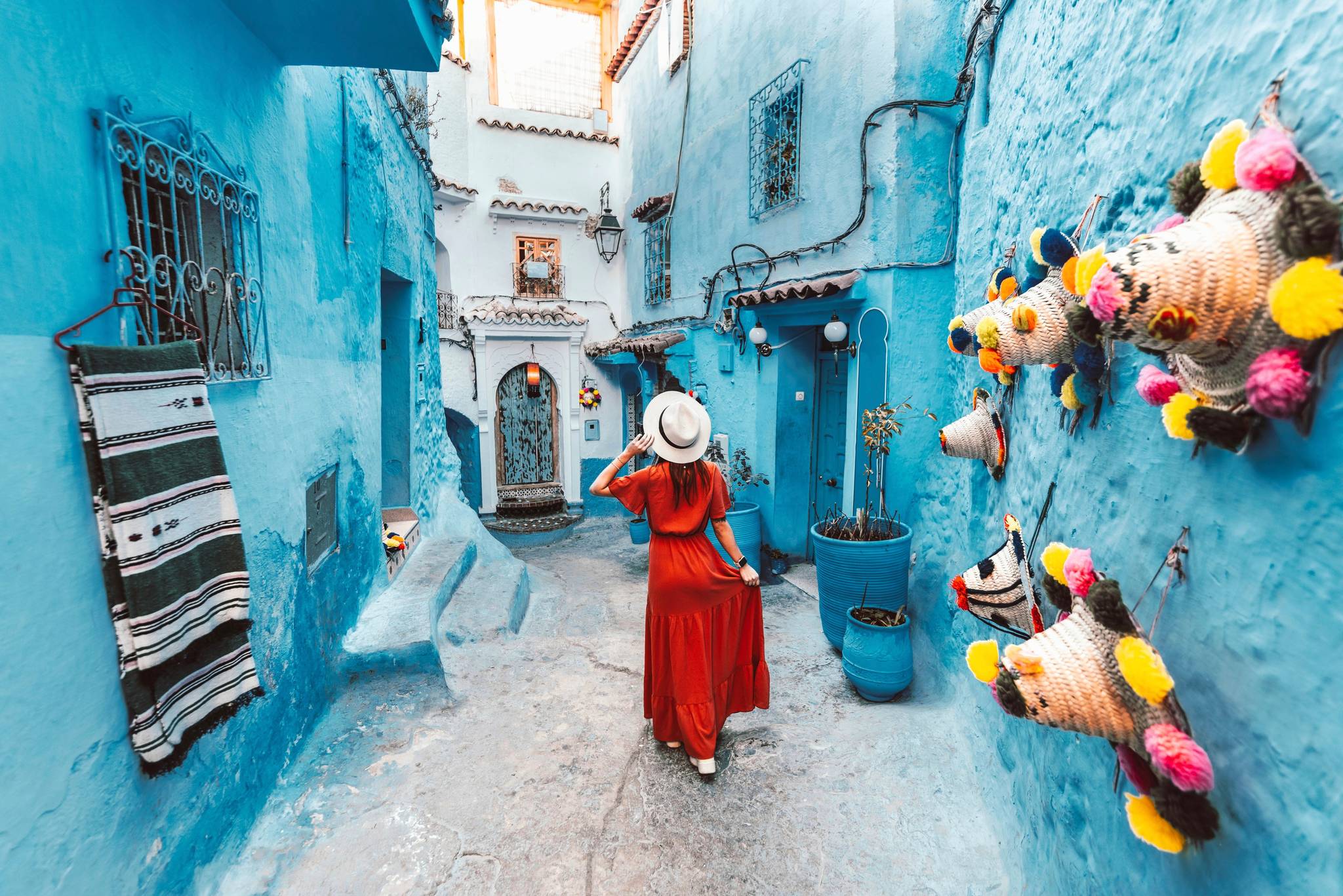 donna con vestito rosso che cammina tra le vie di chefchaouen,