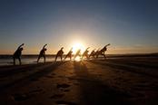 lezione di yoga di gruppo in spiaggia al tramonto