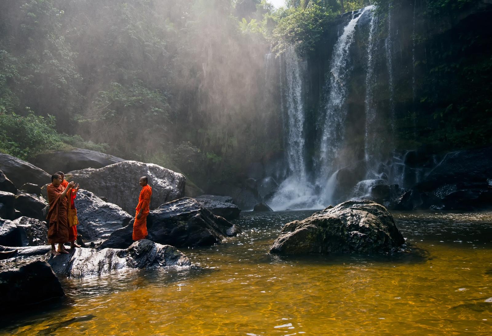 cascata in cambogia con monaci vestiti di arancione